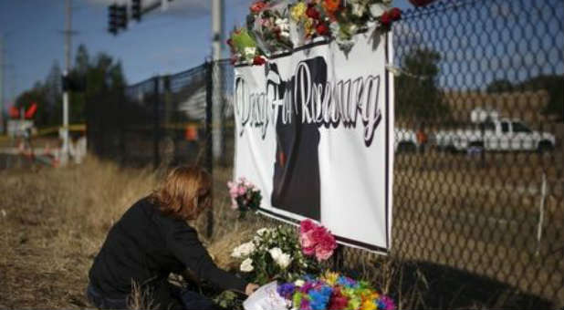 A woman kneels at a memorial to honor the victims of the Umpqua Community College shooting.