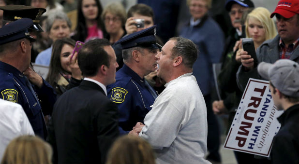 Guards escort a protester out of a rally for Donald Trump