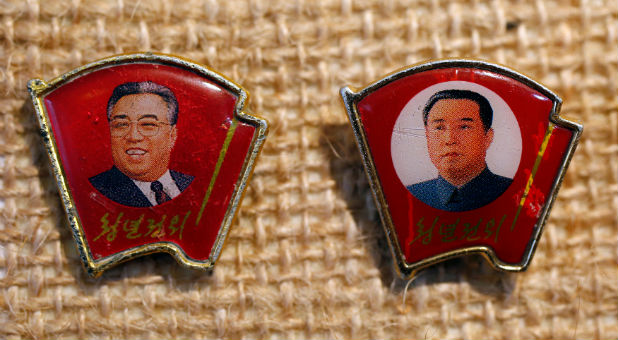 Two pins featuring former North Korean leader Kim Il Sung wearing different facial expressions.