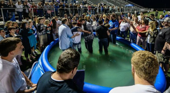 Hundreds of students have recently accepted Christ. Here, students are baptized in an inflatable pool inside the Mingo Central's football stadium.