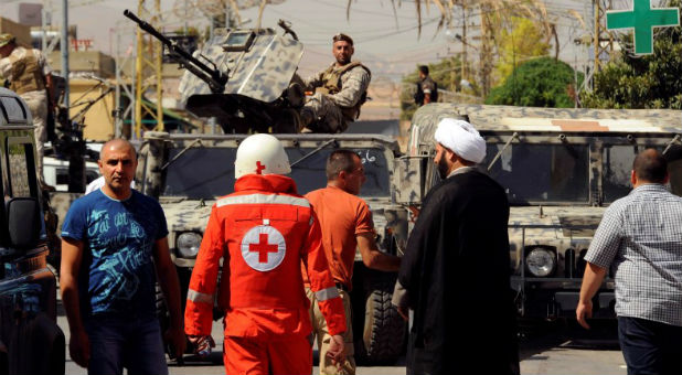 Lebanese army soldiers patrol as a Red Cross member walks near the site where suicide bomb attacks took place in the Christian village of Qaa, in the Bekaa valley, Lebanon