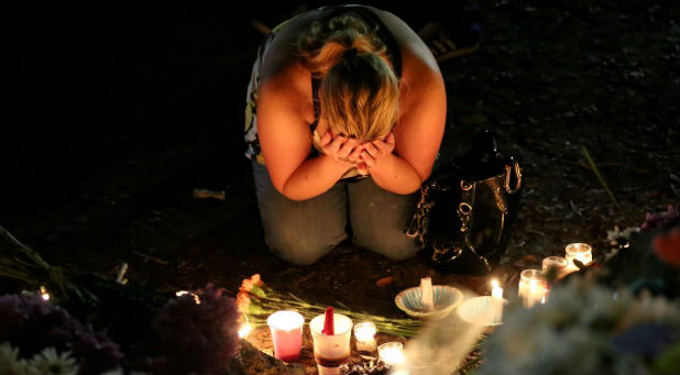 A woman mourns as she sits on the ground and takes part in a vigil for the Pulse night club victims following last week's shooting in Orlando, Florida.