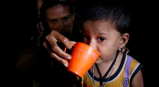 A Rohingya child reacts to the camera as his mother gives him water in Leda unregistered Rohingya Refugee Camp in Cox's Bazar, Bangladesh.