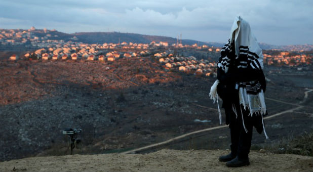 A Jewish man, covered in a prayer shawl, prays in the Jewish settler outpost of Amona in the West Bank December