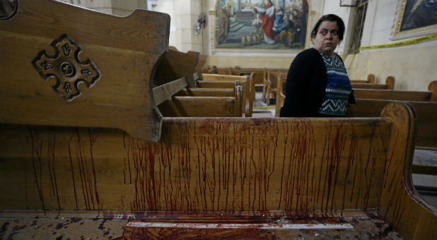 A woman stands near a pew covered in blood inside a Coptic church that was bombed on Sunday in Tanta, Egypt