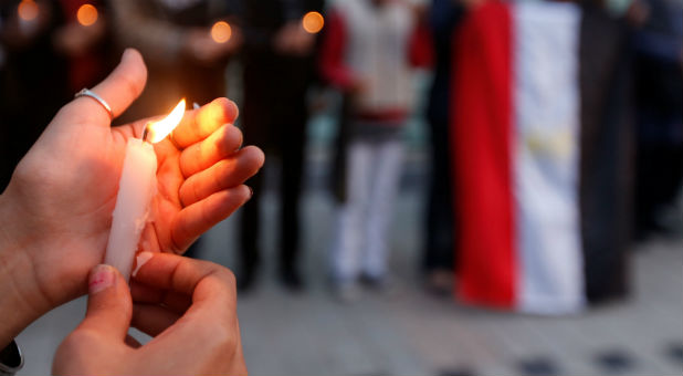 A woman holds a candle as people protest against the twin attacks on Christian churches in Egypt,