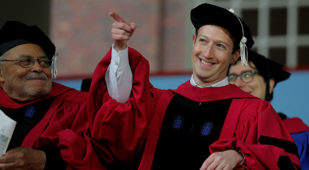 Facebook founder Mark Zuckerberg acknowledges a cheer from the crowd before receiving an honorary Doctor of Laws degree, as fellow honorary degree recipient actor James Earl Jones (L) looks on, during the 366th Commencement Exercises at Harvard University