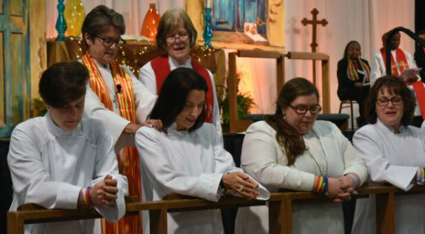 The Rev. M. Barclay, at left, kneels at the Northern Illinois Conference’s commissioning of provisional deacons on June 4 in St. Charles, Illinois