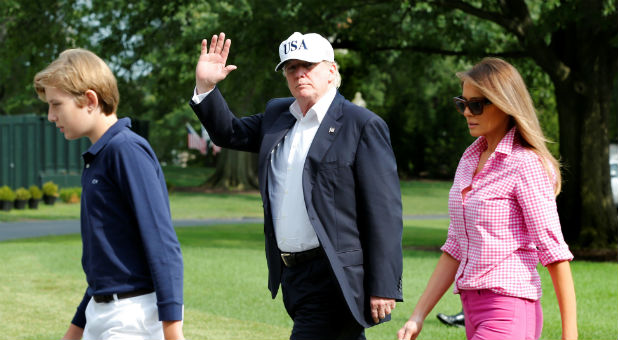 U.S. President Donald Trump waves as he with First Lady Melania Trump and their son Barron walk on South Lawn of the White House upon their return to Washington, U.S., from Camp David, August 27, 2017.