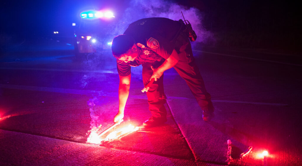 A police officer lays down a safety flare while blocking the road leading to the Arkema SA plant.