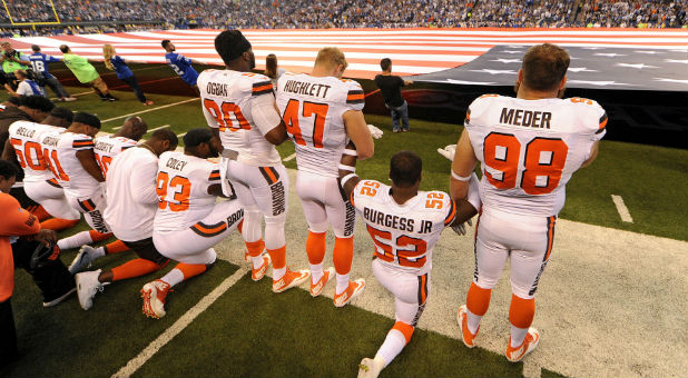The Cleveland Browns team stands and kneel during the National Anthem before the start of their game against the Indianapolis Colts.