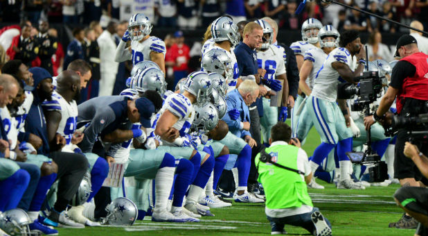 The Dallas Cowboys players, coaches staff and owner Jerry Jones take a knee prior to the National Anthem.