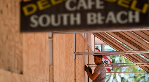 A worker boards up his restaurant in Miami.