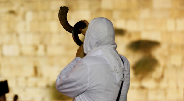 A Jewish worshipper blows a shofar.