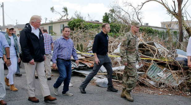 U.S. President Donald Trump walks past hurricane wreckage.