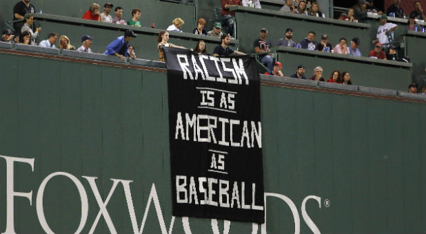 Fans on top of the Green Monster display a racism sign.