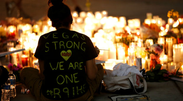 A woman makes a sign at a vigil on the Las Vegas Strip following a mass shooting.
