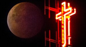 The cross of the Koekelberg Basilica is seen while the moon turns orange during a total