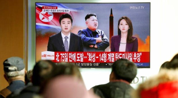 People watch a TV broadcasting a news report on North Korea firing what appeared to be an intercontinental ballistic missile (ICBM) that landed close to Japan.