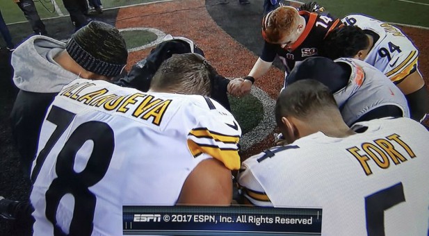 Andy Dalton (14) prays with his opponents for one of their teammates.