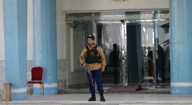 An Afghan security guard stands at the entrance gate of the Intercontinental Hotel after an attack in Kabul.
