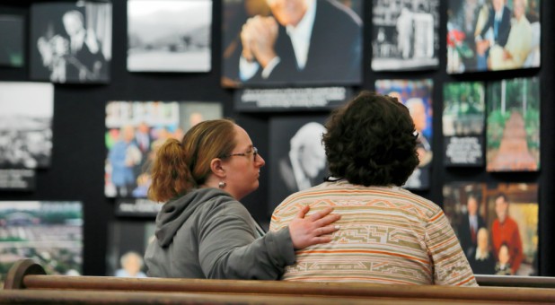 Mourners comfort each other as they sit in a pew near a display of pictures of evangelist Billy Graham, who died Wednesday at his Montreat home aged 99, at Chatlos Memorial Chapel on the grounds of the Billy Graham Training Center in Asheville, North Carolina.