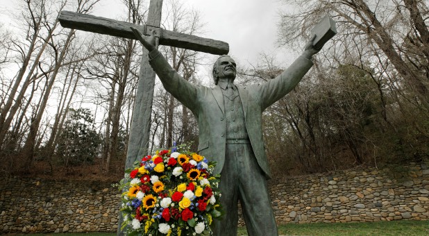 A garland sits under a large bronze statue of evangelist Billy Graham, who died Wednesday at his home aged 99, on the grounds of a Christian conference center in nearby Ridgecrest, North Carolina.
