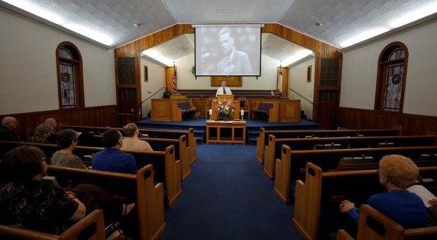 Reverend Bobby Shehan preaches under a projected image of evangelist Billy Graham.