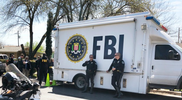 Law enforcement personnel including FBI agents are seen near a home that was hit with a parcel bomb in Austin, Texas.