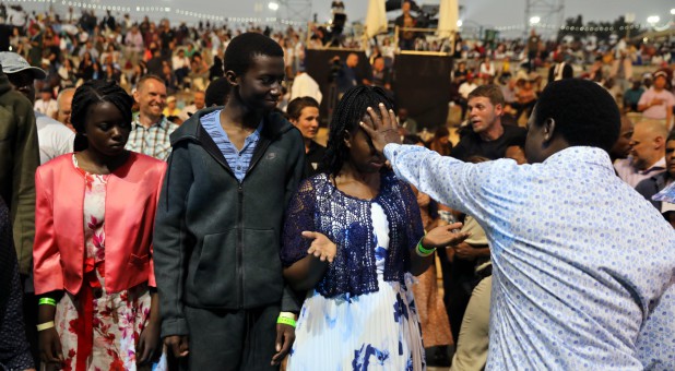 T.B. Joshua, a Nigerian evangelical preacher, places his hand over the face of a woman as he leads a religious retreat on Mount Precipice, Nazareth, northern Israel.