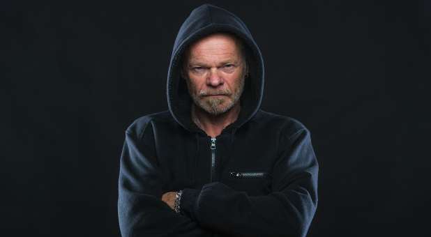 Man wearing hoodie, arms folded, grim expression