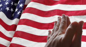 Hands praying with American flag in background