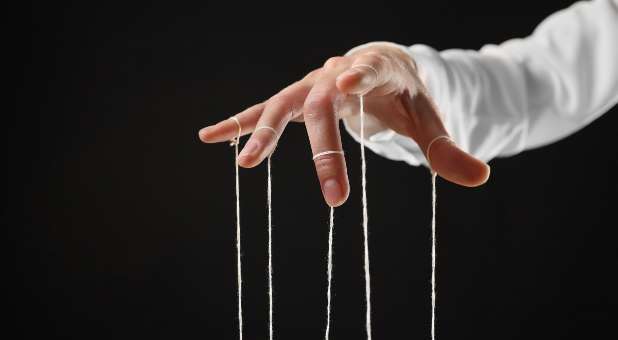 Hand pulling marionette strings from above.